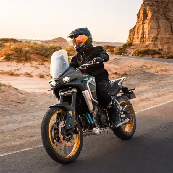 KOVE 800X PRO Adventure-Motorrad fährt auf einer asphaltierten Straße durch felsige Wüstenlandschaft