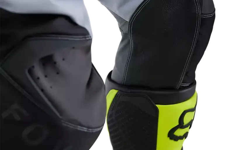 Kniebereich einer Motocross-Hose von Fox mit Lederbesatz und verstärkten Nähten, gelbe Stiefel im Bild
