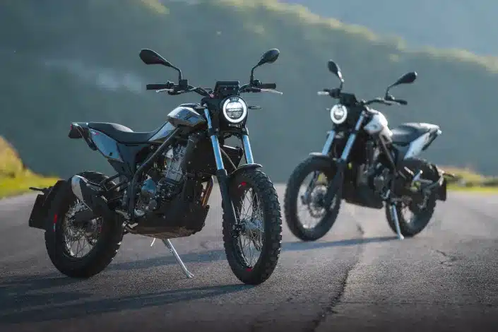 Zwei Beta Alp X Motorräder stehen auf einer Landstraße vor malerischer Bergkulisse.