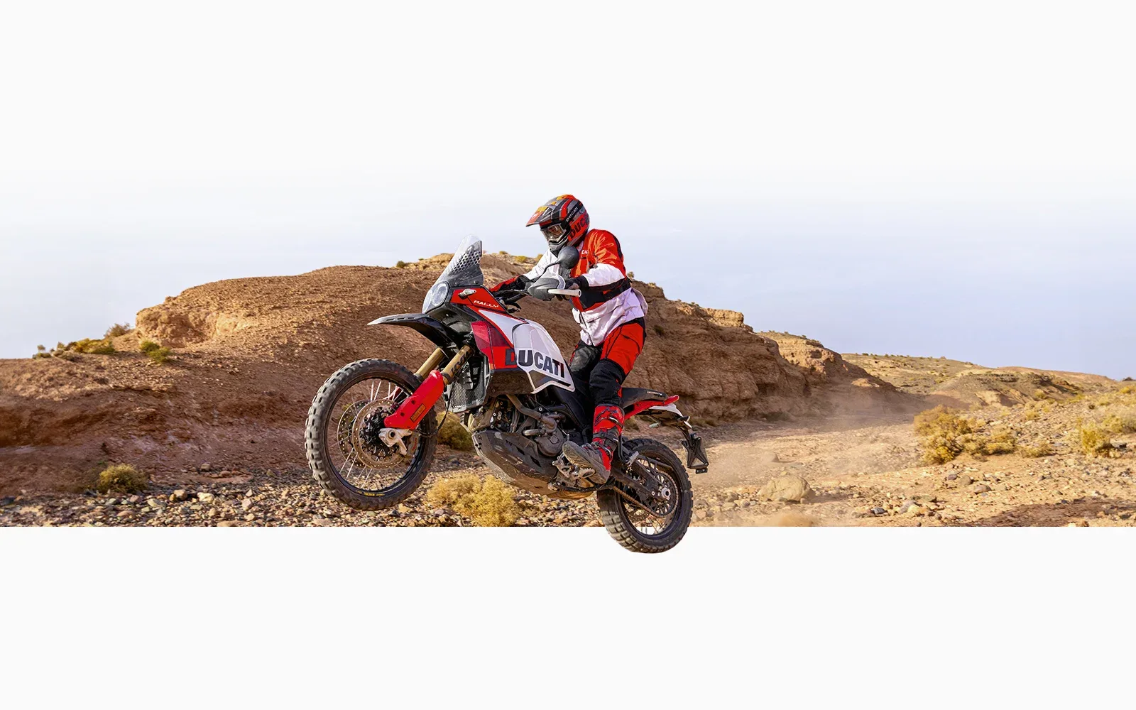 Ducati DesertX Rally wird offroad im Gelände von einem Fahrer in kompletter Motorradausrüstung gesteuert.