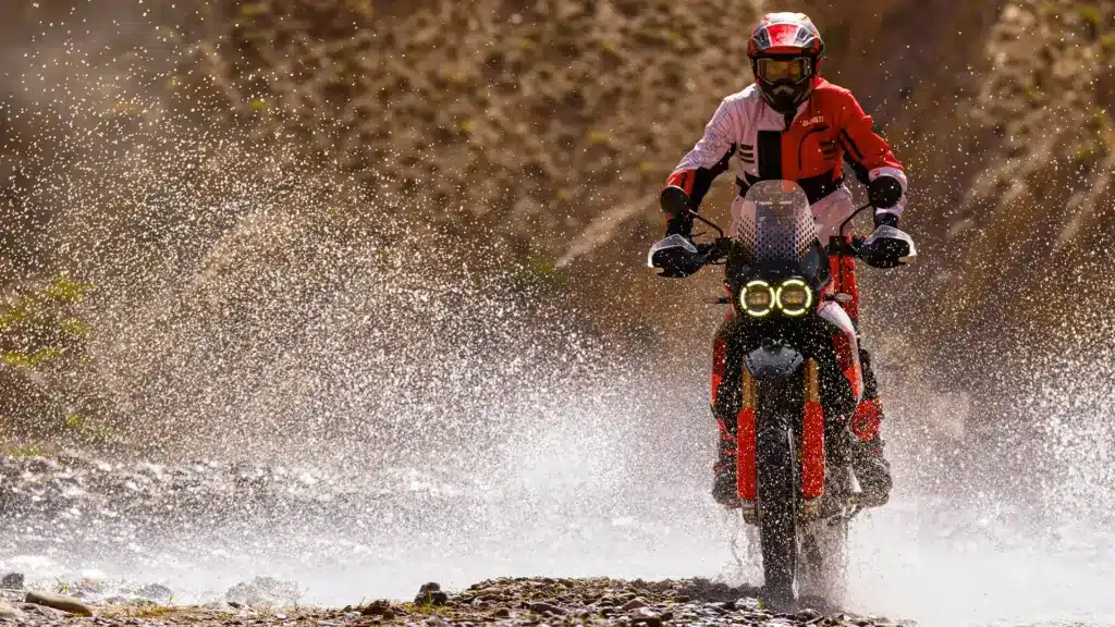 Ducati DesertX Rally fährt offroad durch spritzendes Wasser