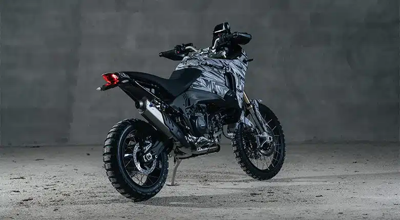 Ducati DesertX V2 in Seitenansicht mit schlankem Design und grobstolliger Bereifung vor grauem Hintergrund
