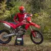 Ducati Desmo450 EDS Enduro-Motorrad in einer herbstlichen Waldumgebung mit Fahrer in roter Ausrüstung.