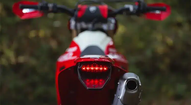 Heckansicht der Ducati Desmo450 EDS mit leuchtendem LED-Rücklicht und Auspuff