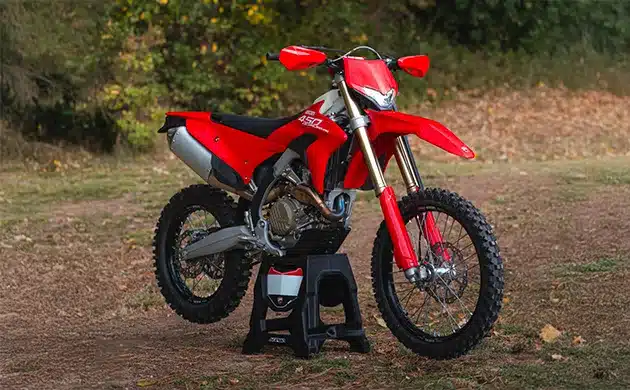 Rotes Offroad-Motorrad mit Ständer auf naturbelassenem Untergrund