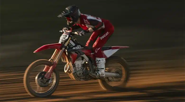 Motocross-Fahrer mit Ducati Desmo450 MX Factory im Renneinsatz auf sandiger Strecke.