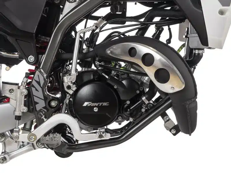 Detailaufnahme des Motors und Auspuffsystems einer Fantic XE 50 Performance 2025 Enduro mit Fokus auf Rahmen und Auslasssteuerung.