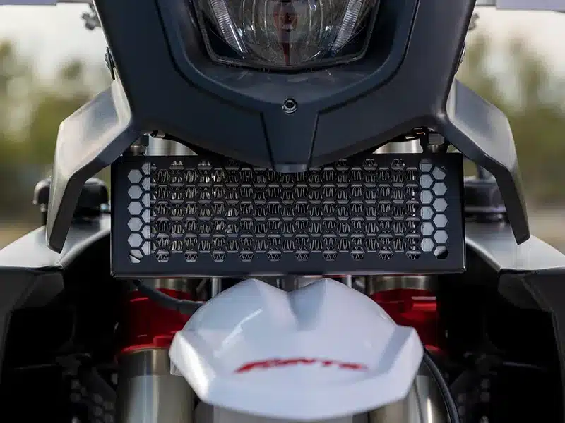 Nahaufnahme des Ölkühlers und der Frontmaske der Fantic XEF Rally Factory, darunter das Fantic-Logo auf dem weißen Kotflügel