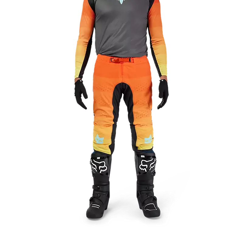 Flexair Grid Hose in Schwarz/Orange, getragen von einer Person mit Motocross-Stiefeln und Handschuhen, Vorderansicht.