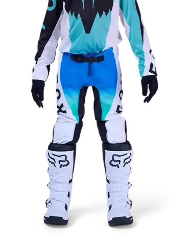 Jugendliche Motocross-Fahrerin trägt die blaue Fox Flexair Spire Hose mit Schutzstiefeln auf weißem Hintergrund