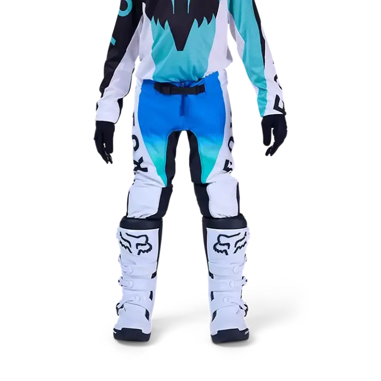 Jugendliche Motocross-Fahrerin trägt die blaue Fox Flexair Spire Hose mit Schutzstiefeln auf weißem Hintergrund