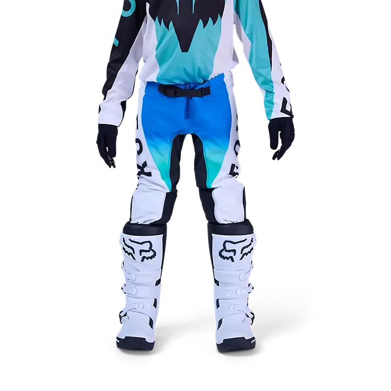 Jugendliche Motocross-Fahrerin trägt die blaue Fox Flexair Spire Hose mit Schutzstiefeln auf weißem Hintergrund