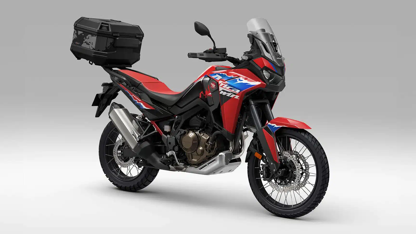Honda CRF1100L Africa Twin 2024 mit rotem Lack, Topcase und hoher Scheibe vor neutralem Hintergrund.