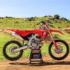 Honda CRF250R 2025 als Motocross-Motorrad vor einer Offroad-Strecke im Grünen