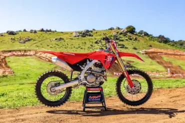 Honda CRF250R 2025 als Motocross-Motorrad vor einer Offroad-Strecke im Grünen