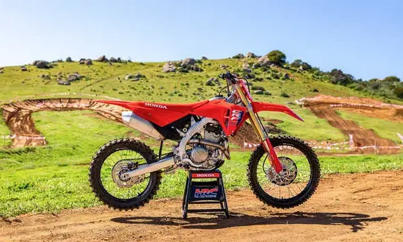 Honda CRF250R 2025 als Motocross-Motorrad vor einer Offroad-Strecke im Grünen