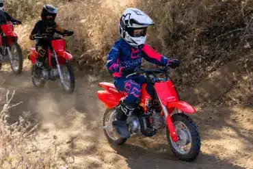 Kinder fahren mit der Honda CRF50F auf einer staubigen Offroad-Strecke.