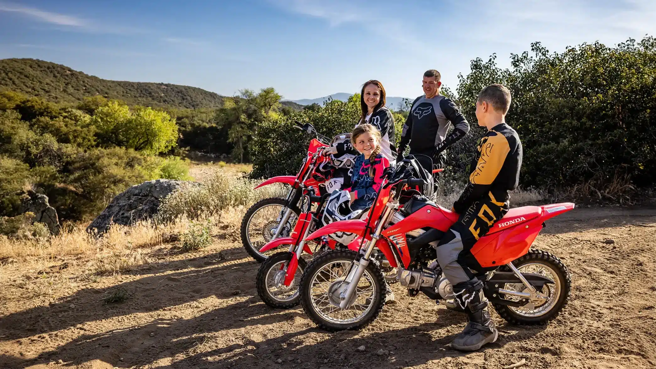 Familie mit Kindern und Erwachsenen auf Honda CRF50F und größeren Honda Offroad-Motorrädern im Gelände
