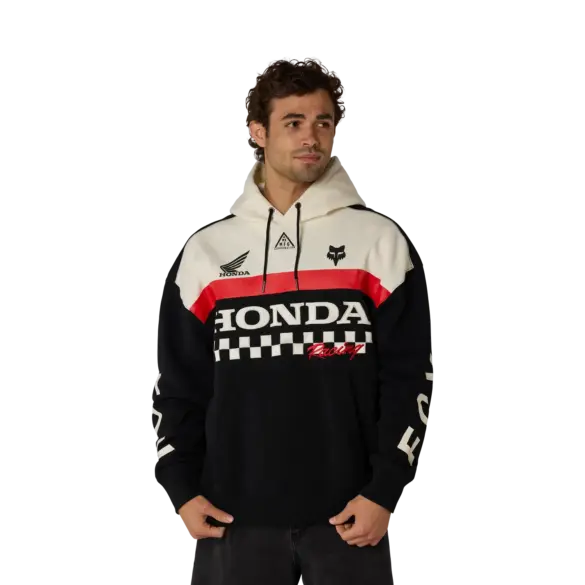 Modell trägt einen Honda Heavyweight Pullover Hoodie in Schwarz mit weißen und roten Akzenten, Honda- und Fox-Logos auf der Brust, klassischen Motorsport-Grafiken und Kapuze.