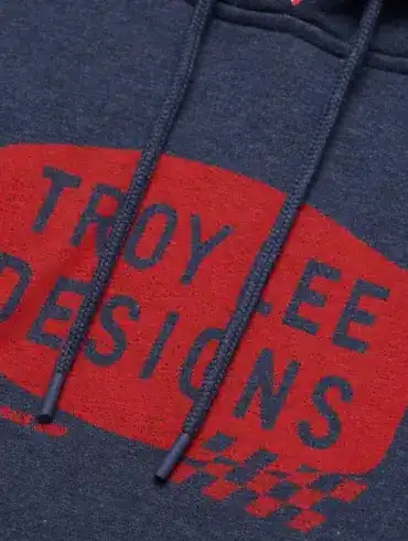 Nahaufnahme des Troy Lee Designs Kapuzenpullovers Stamp Navy Heather mit rotem Stamp-Motiv auf navy meliertem Stoff.