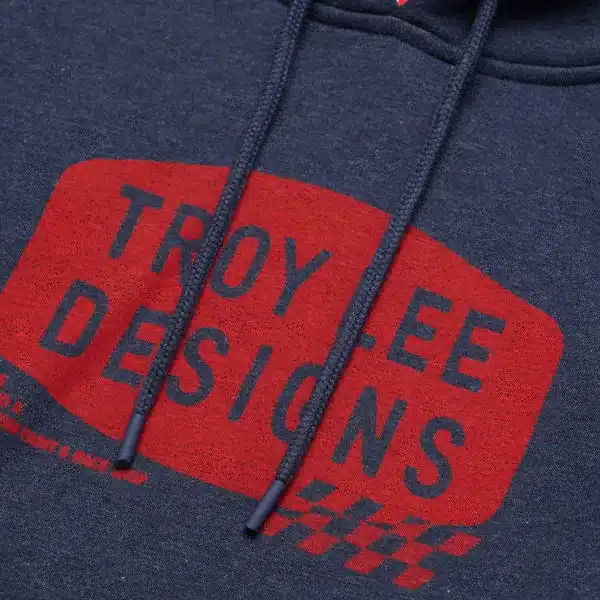 Nahaufnahme des Troy Lee Designs Kapuzenpullovers Stamp Navy Heather mit rotem Stamp-Motiv auf navy meliertem Stoff.
