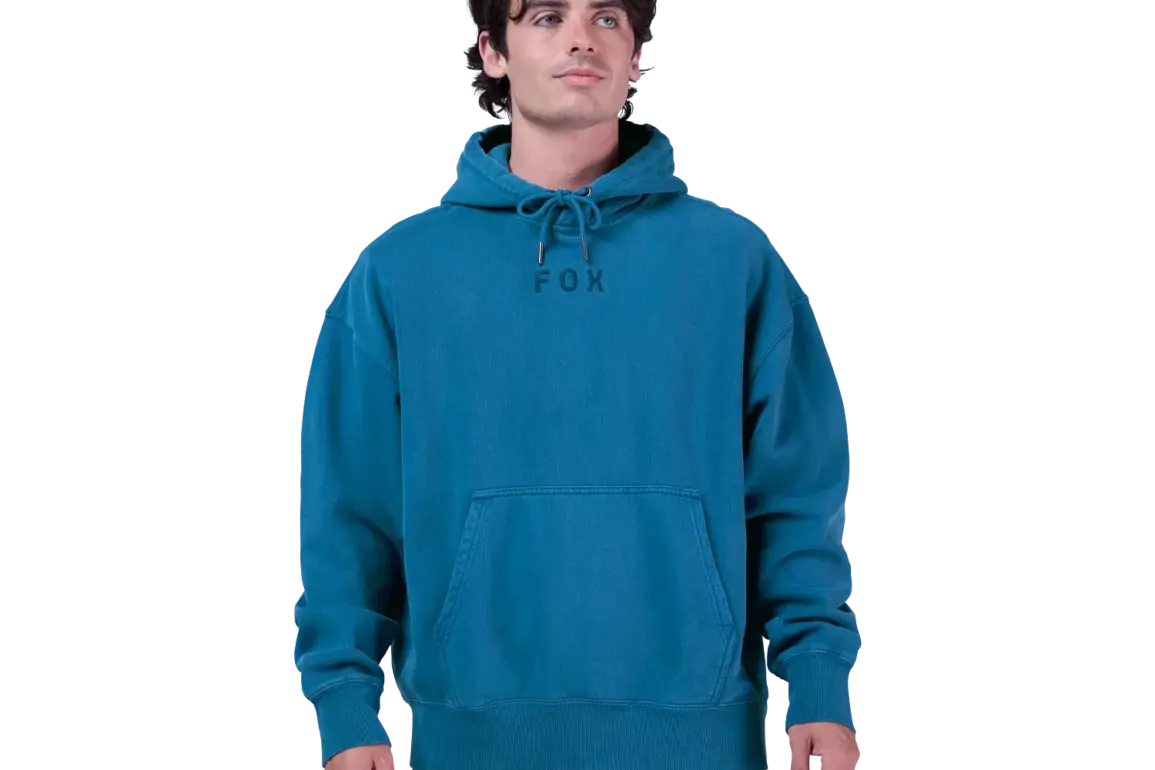 Ein Mann trägt den oversized Wordmark Kapuzenpullover von Fox in Türkis mit Kordelzug und Kängurutasche.