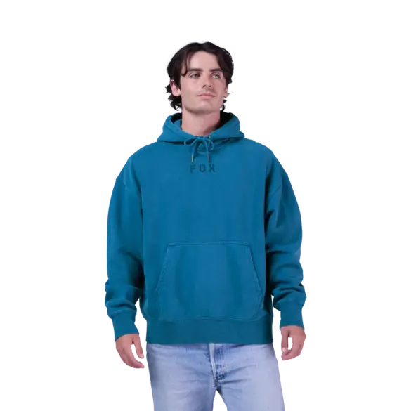 Ein Mann trägt den oversized Wordmark Kapuzenpullover von Fox in Türkis mit Kordelzug und Kängurutasche.