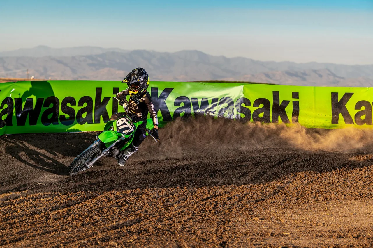 Junger Fahrer fährt Kawasaki KX65 2026 im Motocross-Outfit auf abgesteckter Strecke.