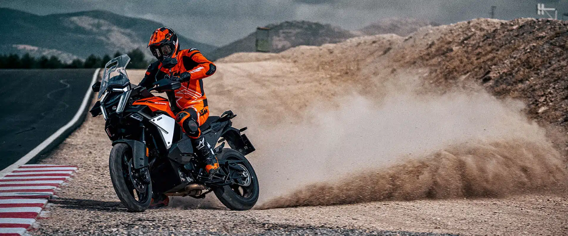 KTM 1390 Super Adventure S EVO fährt auf Schotter und wirbelt Staub auf.