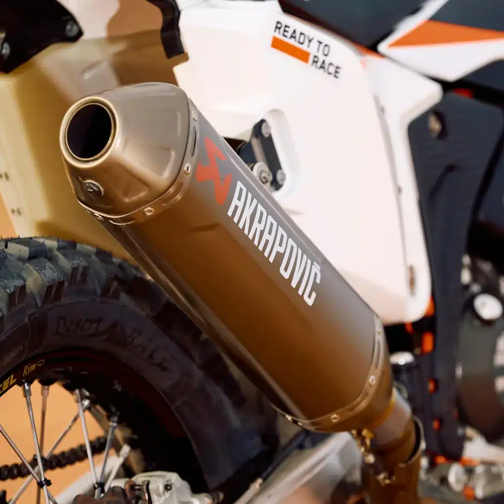 Akrapovič-Titanauspuff an einer KTM 450 Rally Replica 2026, Detailansicht Hinterrad und Auspuffanlage.