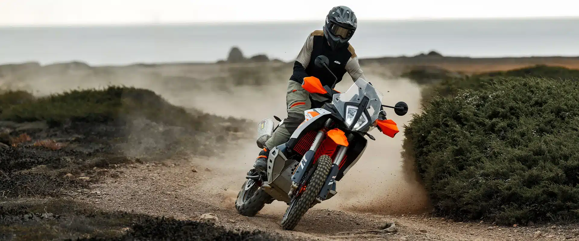 KTM 890 Adventure R 2026 fährt Offroad über eine staubige Schotterpiste.