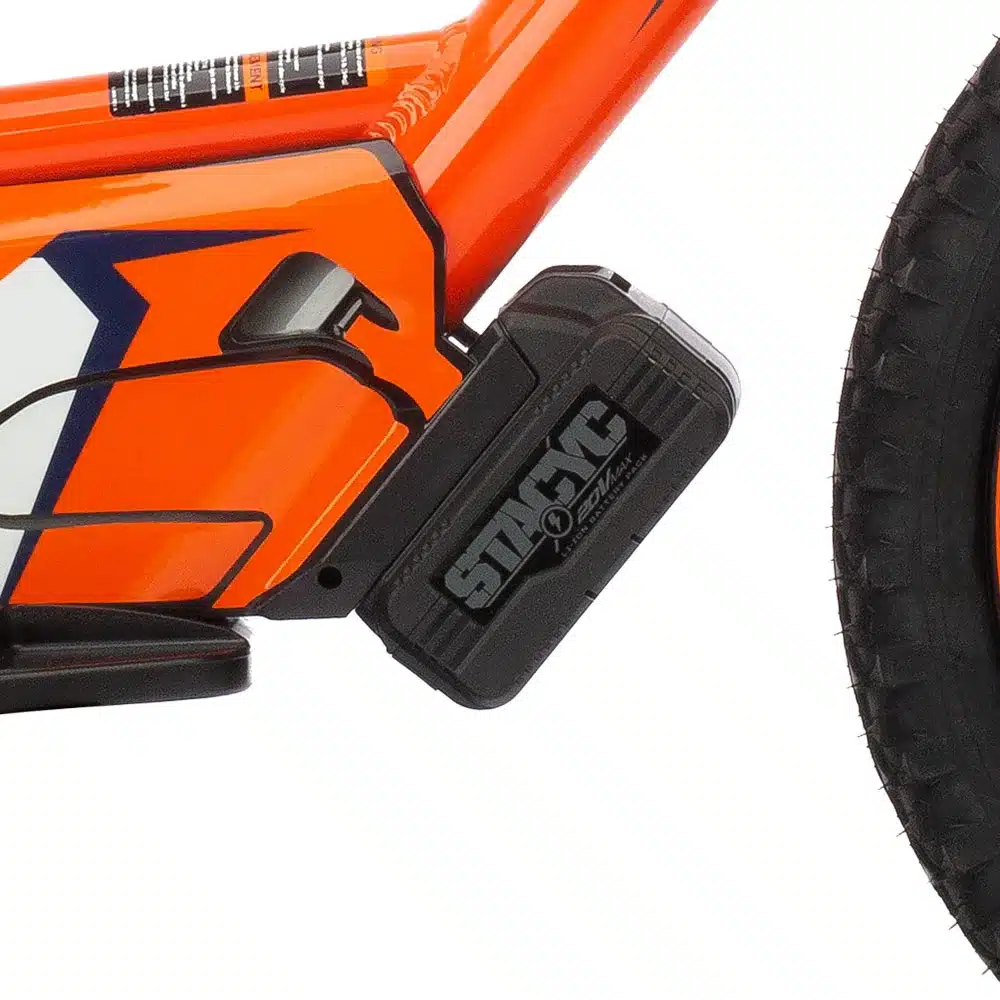 Nahaufnahme des Akkus und Rahmenbereichs einer KTM SX-E 1.12 mit orangefarbenem Design und Stollenreifen.