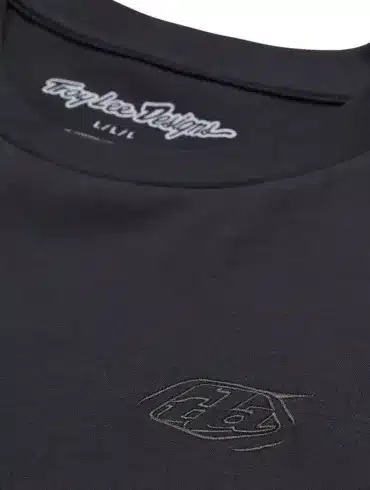 Detailaufnahme eines schwarzen Troy Lee Designs Kurzarm-T-Shirts mit dezentem Logo auf der Brust und Schriftzug im Nackenbereich.