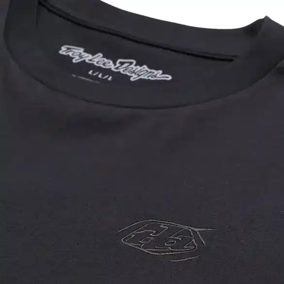 Detailaufnahme eines schwarzen Troy Lee Designs Kurzarm-T-Shirts mit dezentem Logo auf der Brust und Schriftzug im Nackenbereich.
