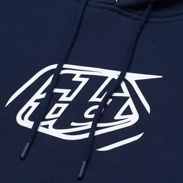 Nahaufnahme des Brustbereichs eines navyblauen Hoodie mit weißem Abzeichen von Troy Lee Designs.