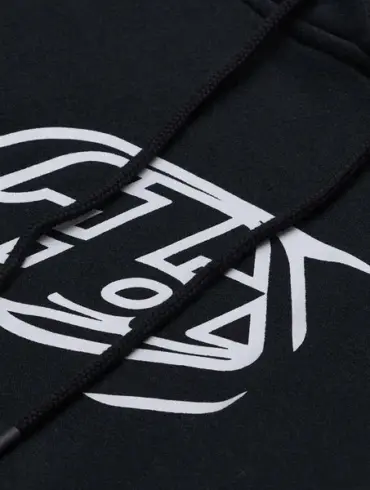 Nahaufnahme eines schwarzen Hoodies mit weißem Badge-Aufdruck und Kapuzenkordeln.