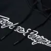 Schwarzer Troy Lee Designs Signature-Hoodie mit weißem Logo-Schriftzug, Detailansicht der Brustpartie.