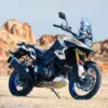 Suzuki V-Strom 1050DE Motorrad, stehend im Gelände vor Felsen, Seitenansicht