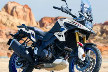 Suzuki V-Strom 1050DE Motorrad, stehend im Gelände vor Felsen, Seitenansicht