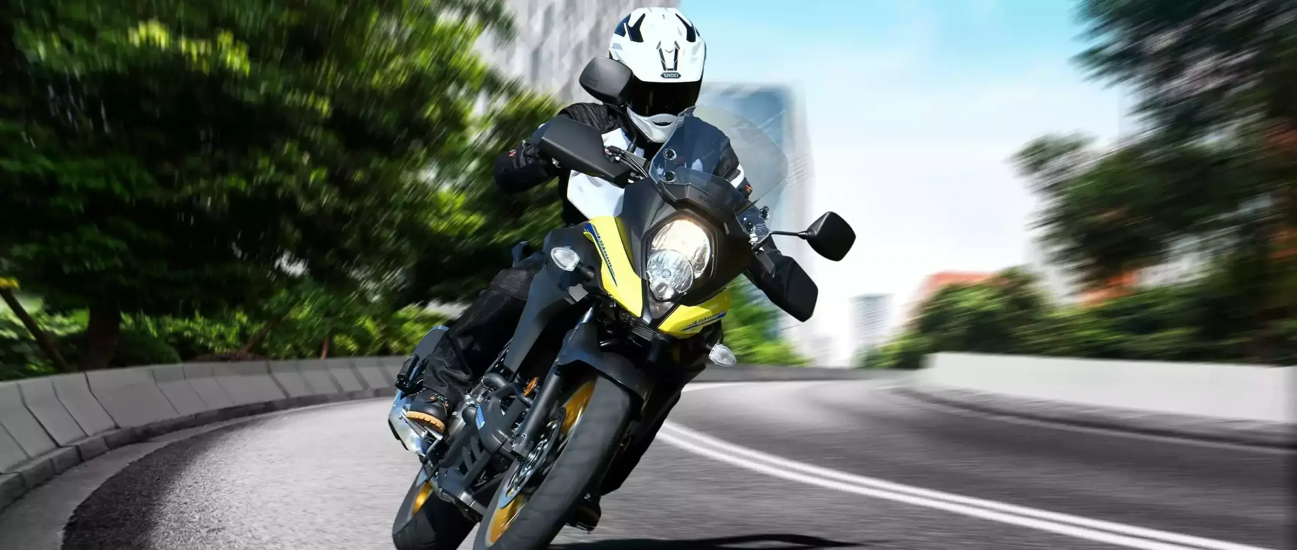 Motorradfahrer fährt Suzuki V-Strom 650 in einer städtischen Kurve.