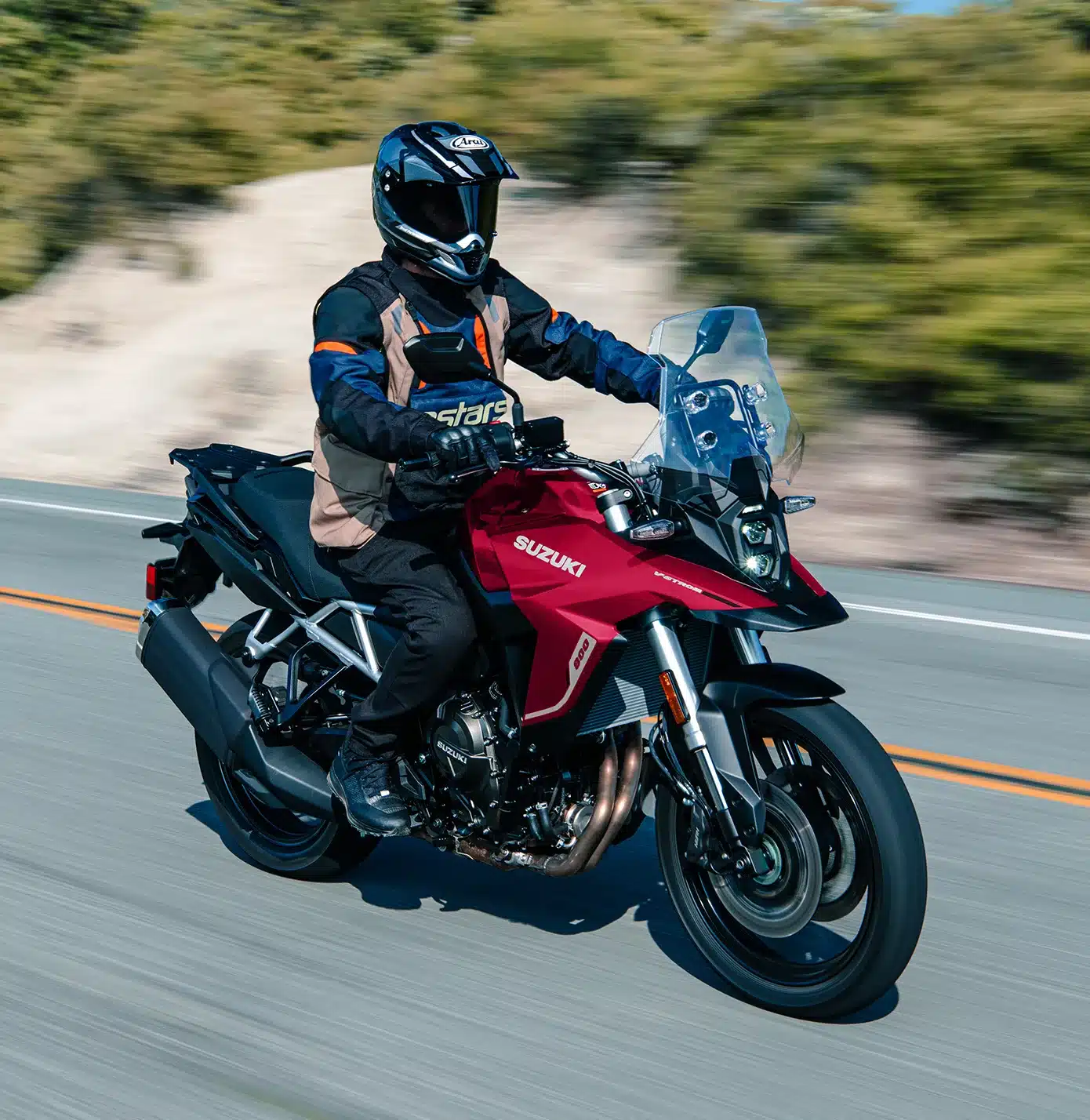 Motorradfahrer auf einer roten Suzuki V-Strom 800 fährt auf einer Landstraße