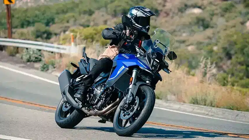 Ein Fahrer bewegt die blaue Suzuki V-Strom 800 Power Edition mit Akrapovič Slip-On-Endschalldämpfer dynamisch durch eine Kurve.