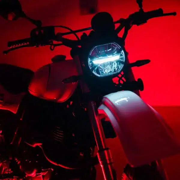 Nahaufnahme des Frontbereichs der SWM Silver Vase T 650 mit leuchtendem LED-Scheinwerfer, roter Hintergrund