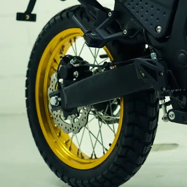 Nahaufnahme des goldenen 18-Zoll-Hinterrads der SWM Silver Vase T 650 mit Enduroreifen und Bremsscheibe