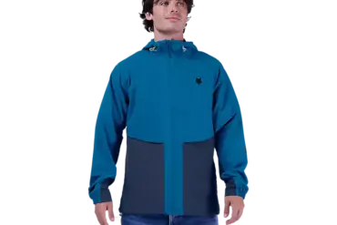 Ein Mann trägt die blaue Survivalist Windjacke mit Kapuze und Reißverschluss.
