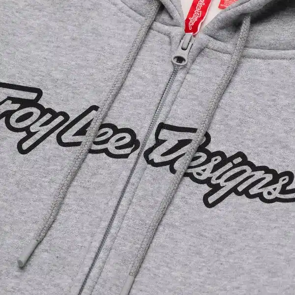 Detailansicht des Zip Up Hoodie Signature Grey Heather mit sichtbar eingesticktem Troy Lee Designs Logo und Reißverschluss.