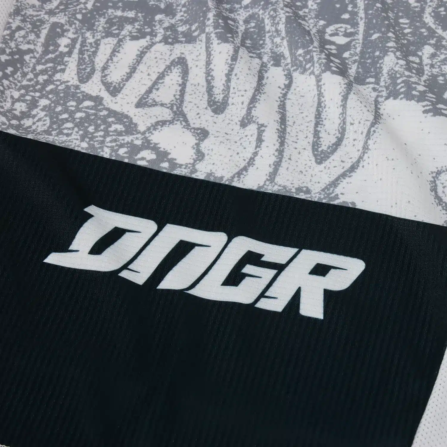 Detailfoto des weißen Fox DNGR Motocross-Trikots mit prominentem schwarzen DNGR-Logo