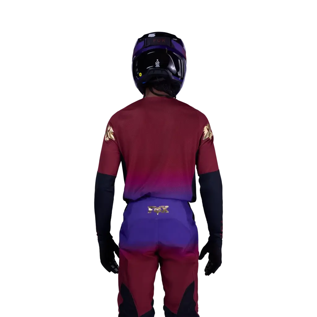 Rider in voller Motocross-Kleidung, Rückansicht des 360 Drip Jerseys von Fox Racing in Rostbraun und Blau.