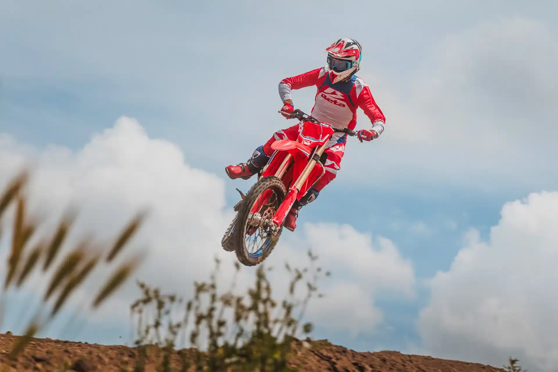 Motocross-Fahrer springt mit roter Beta RX 450 4T über eine Geländestrecke