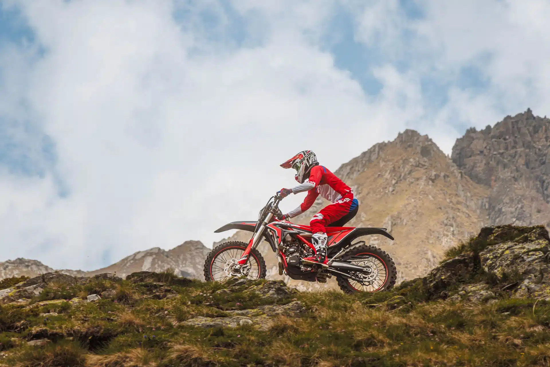 Ein Fahrer auf einer Beta Xtrainer 300 fährt abseits der Straße in einer alpinen Landschaft bergauf.